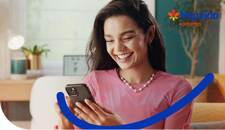 Mulher sorrindo olhando para o celular que esta em mãos