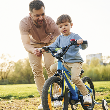 Pai ensinando filho a andar de bicicleta